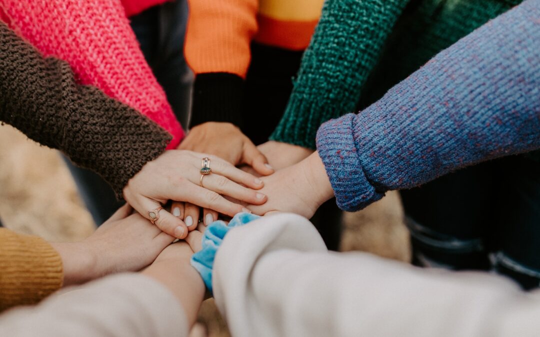 Circle of friends with hands piled in the middle showing togetherness.